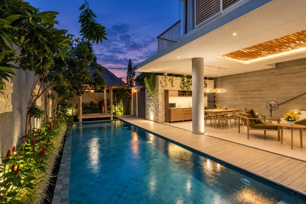 Villa Swan 02 — pool, lit at dusk beside the timber deck and the open-air living room