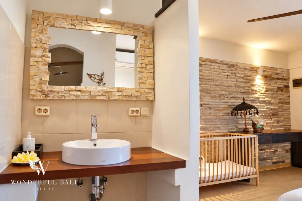3BR villa for rent in Tabanan — vanity with stone-framed mirror and a baby cot in the next room