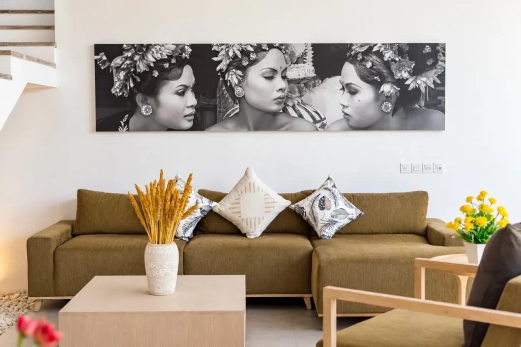 Villa Swan 02 — living, brown sofa with woven cushions below a canvas of Balinese dancers