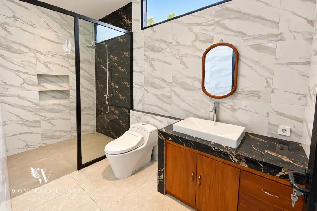 3BR villa for sale or rent in Sanur — bathroom vanity with oval mirror and glass shower