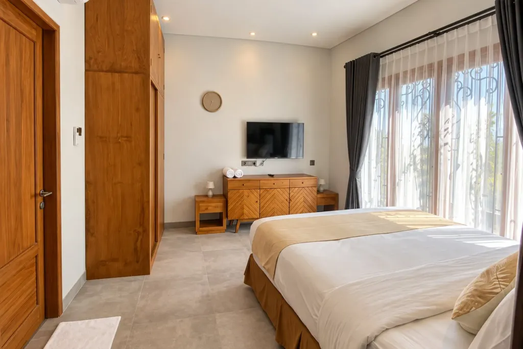 3BR villa for rent in Sanur — main bedroom with sunlit French windows and teak dresser