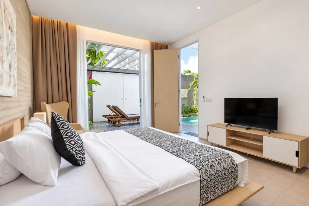 Villa Swan 02 — bedroom 2, king bed facing a smart TV, sliding doors onto the pool terrace