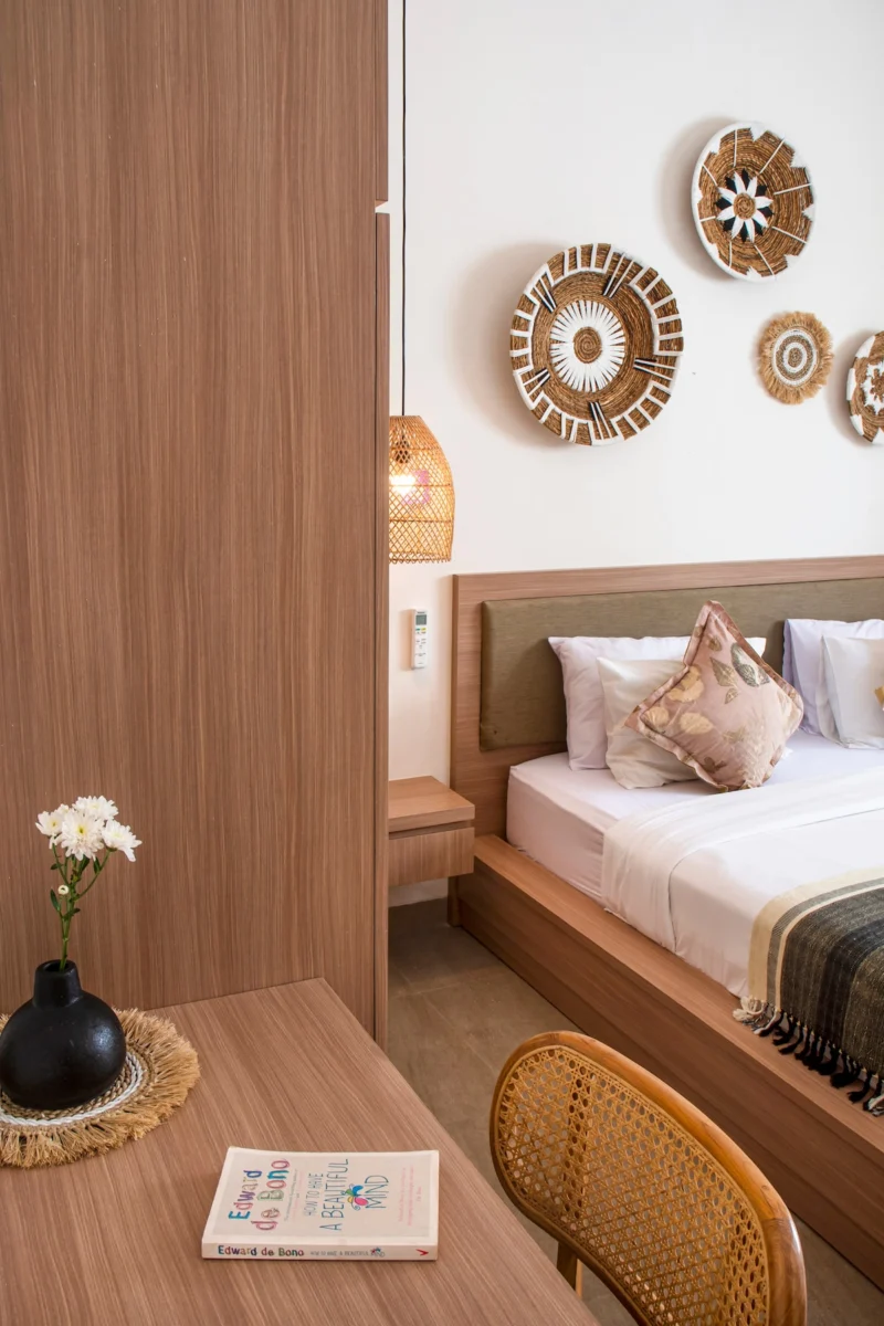 Villa LaBumbak, Umalas — bedroom 2, desk with cane chair and a single flower in a black vase, bed alongside beneath the woven discs