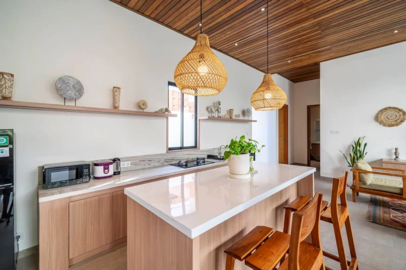 Villa LaBumbak, Umalas — kitchen, white stone island with timber bar stools, hob and microwave along the counter, rattan pendants overhead