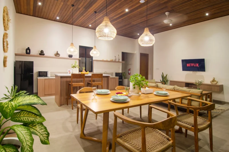 Villa LaBumbak, Umalas — dining, timber dining table laid for four, kitchen island and fridge behind, rattan pendants overhead