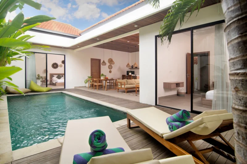 Villa LaBumbak, Umalas — pool, daytime pool with sunloungers and rolled towels, bedroom and living room behind glass under a terracotta roofline