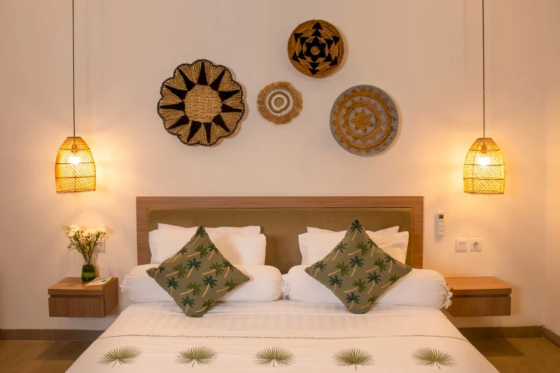 Villa LaBumbak, Umalas — bedroom 1, king bed with palm-print cushions beneath woven wall discs, rattan pendants lit warm either side