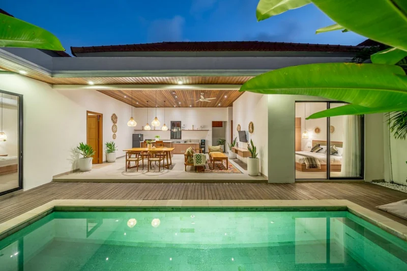 Villa LaBumbak, Umalas — pool, green-lit pool at dusk with the open-plan living room and kitchen glowing behind