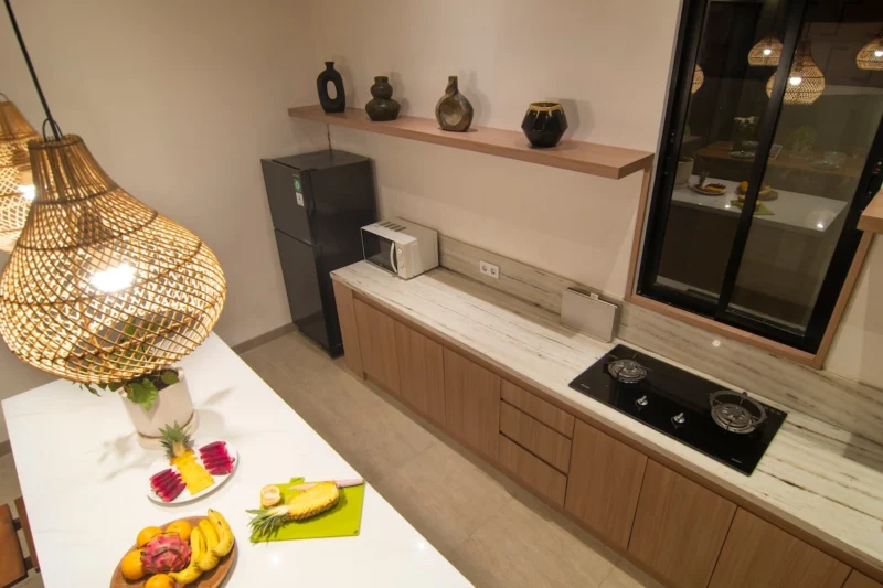 Villa LaBumbak, Umalas — kitchen, counter with hob and fridge, fresh fruit platter on the stone worktop, rattan pendant overhead