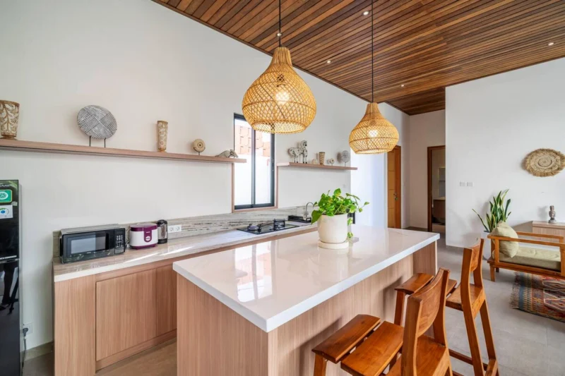 Villa LaBumbak, Umalas — kitchen, white stone island with timber bar stools, hob and microwave along the counter, rattan pendants overhead