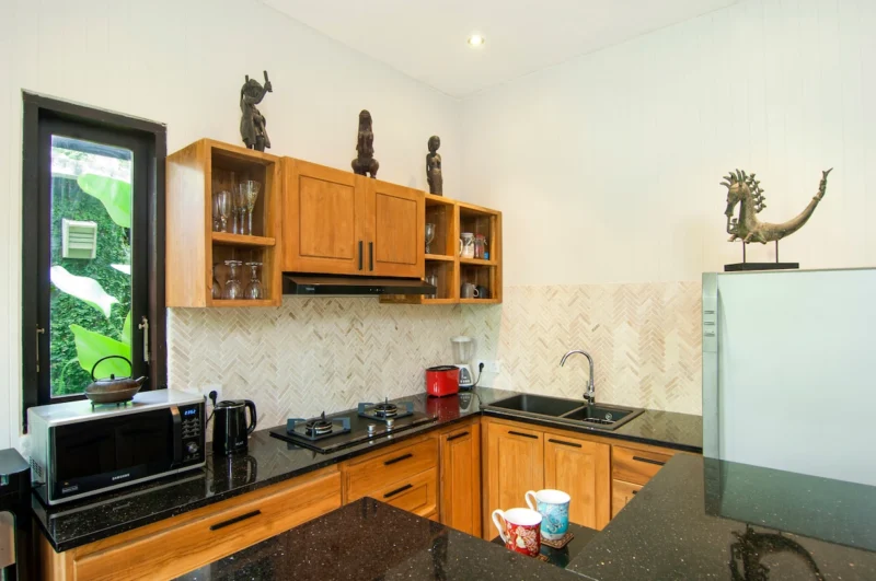 Prepare meals in the open kitchen while enjoying the green garden of the villa.