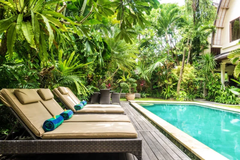 Sun loungers by the pool surrounded by lush garden.