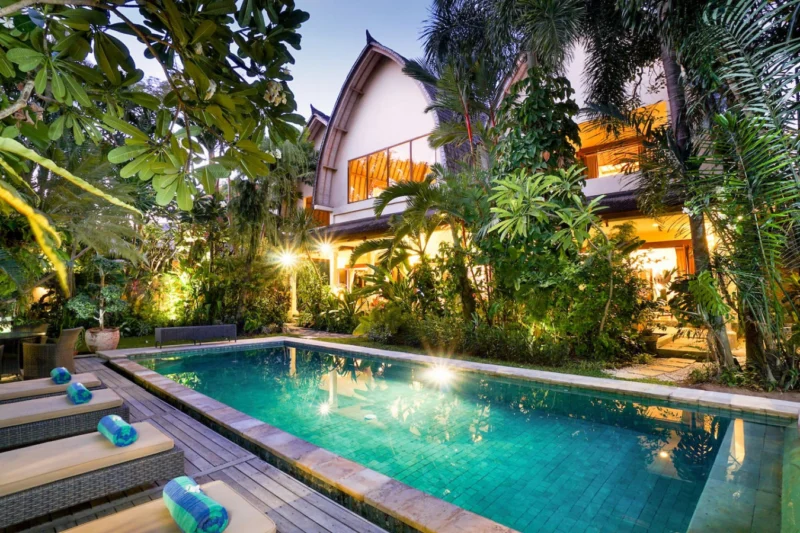 Inviting pool with lush garden and villa backdrop.