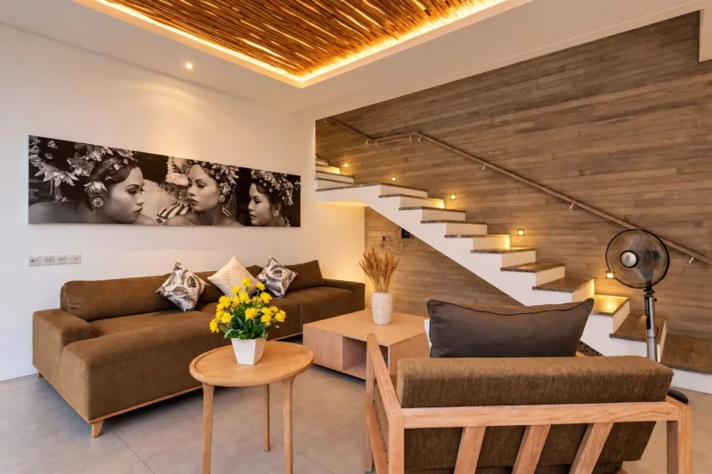 Villa Swan 01 — living, sectional sofa, rattan armchair and timber stair lit by warm cove lighting