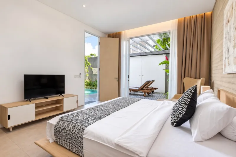 Villa Swan 01 — bedroom 2, king bed facing a smart TV, sliding doors onto the pool terrace